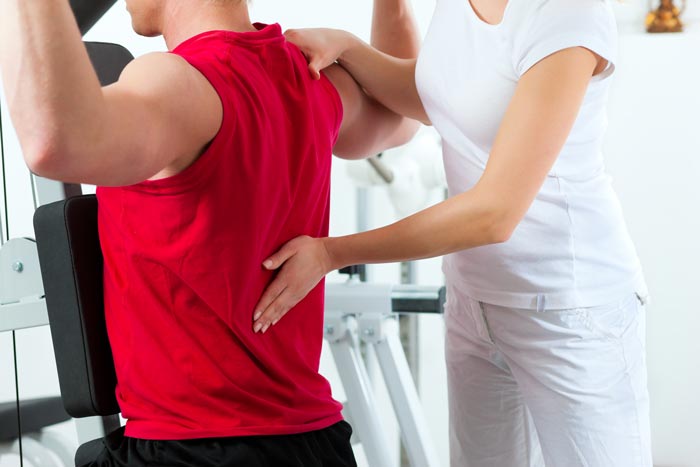 physical therapist holding man's middle back