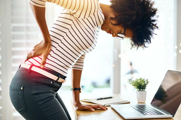 woman in striped shirt holding lower back in pain
